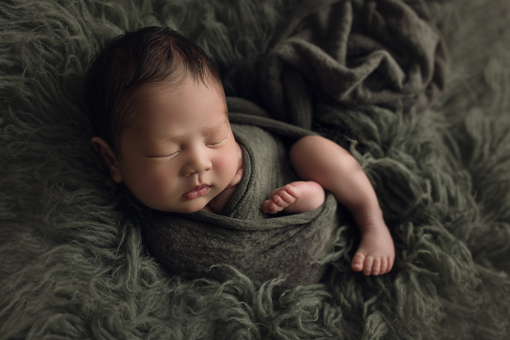Newborn Baby Boy on green fur in matching green wrap