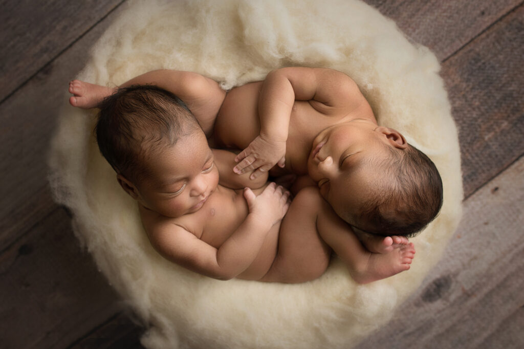 two of the triplet girls laying in a bowl hugging