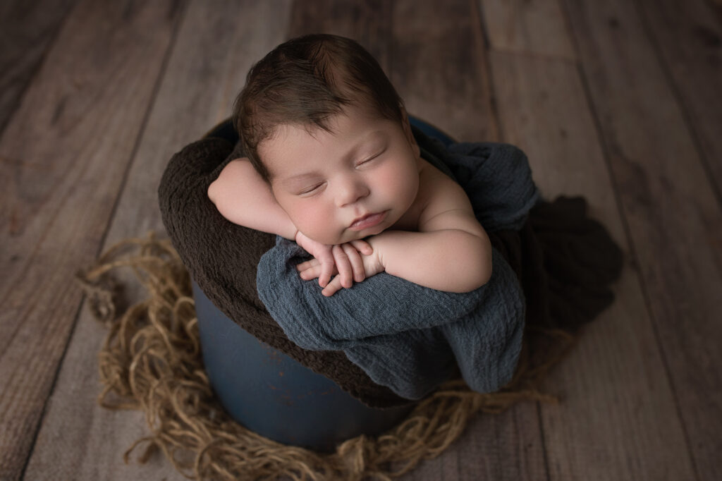 Newborn Baby boy face forward in a blue bucket