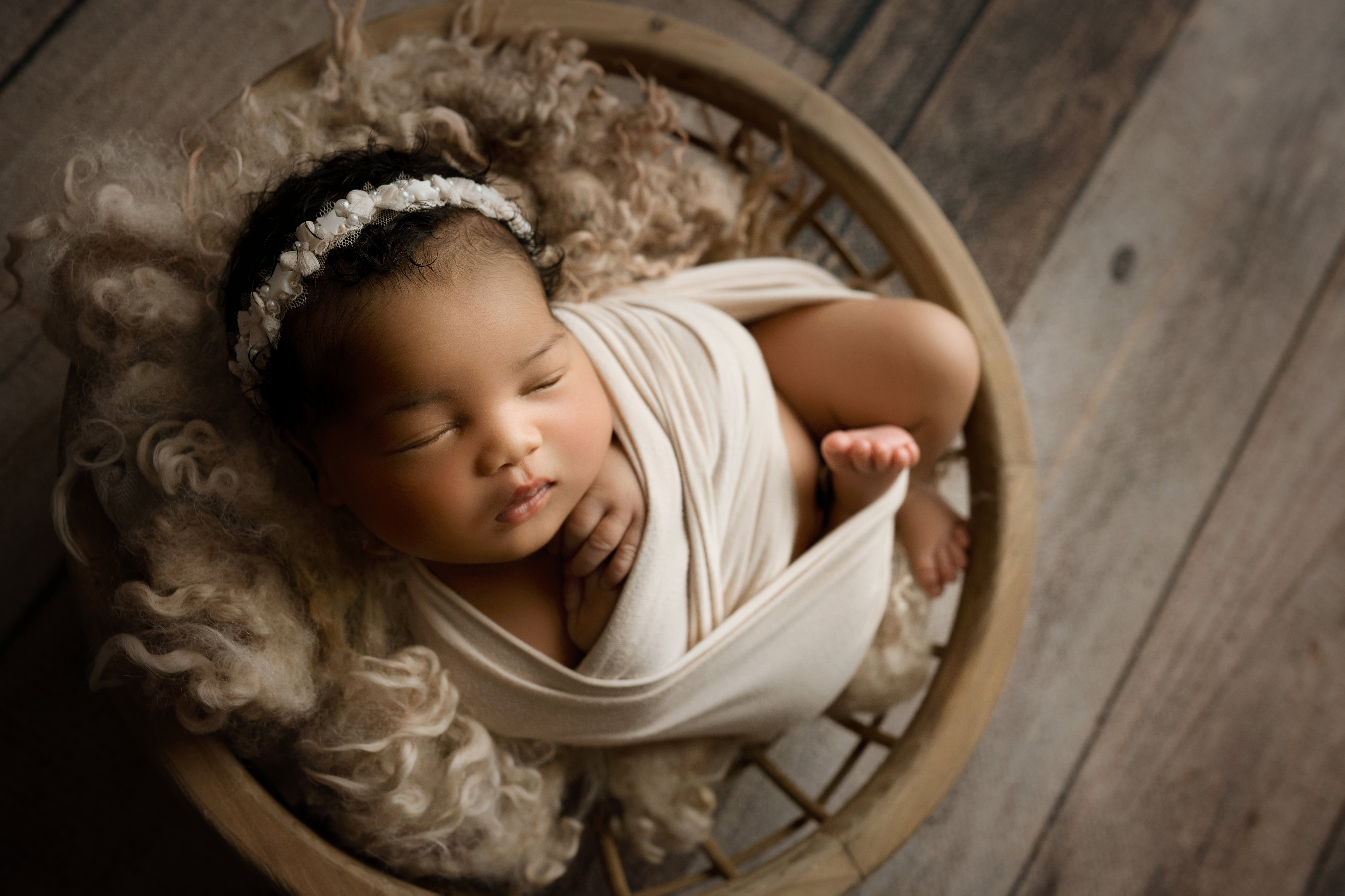 ### Newborn baby girl in cream furs with matching wrap in a bowl