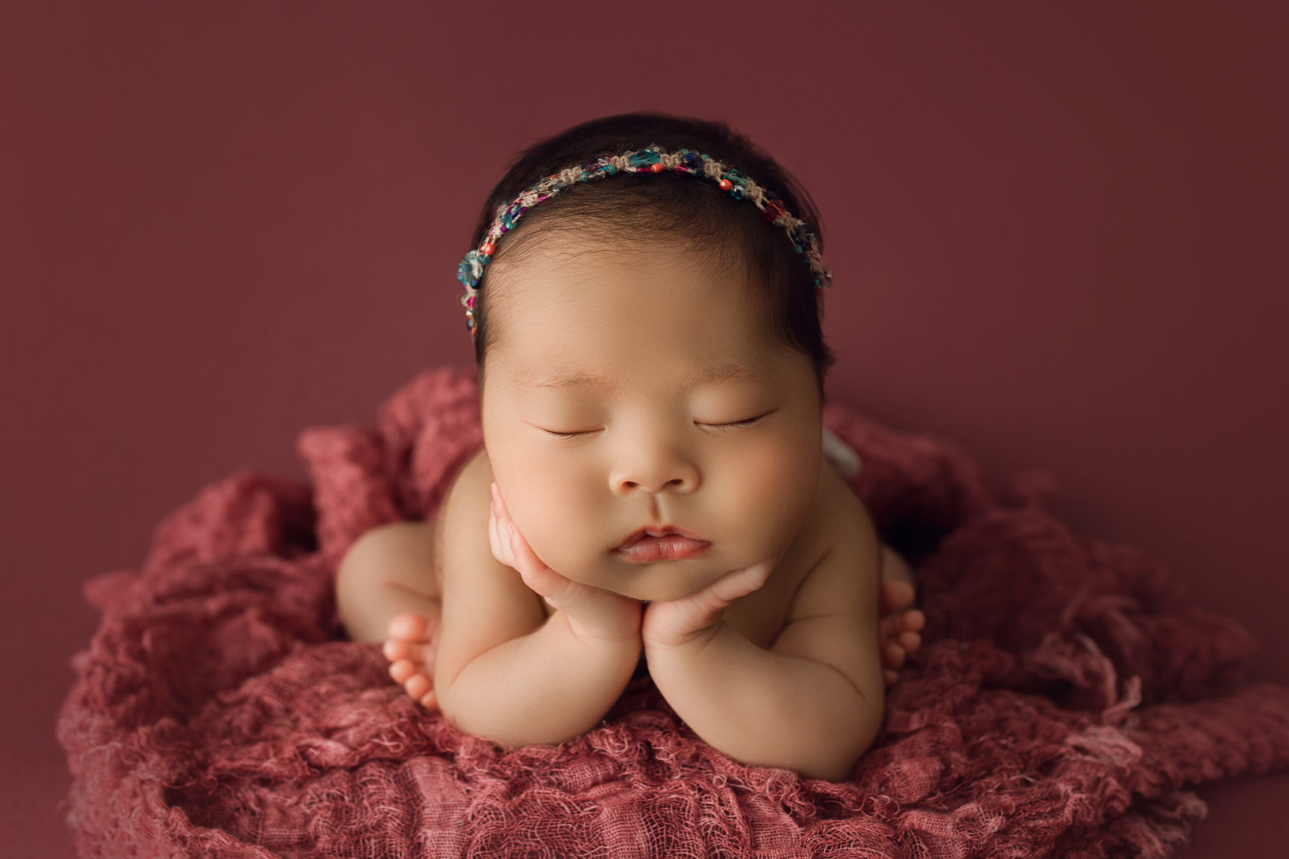 newborn baby girl on pink blanket in froggy pose