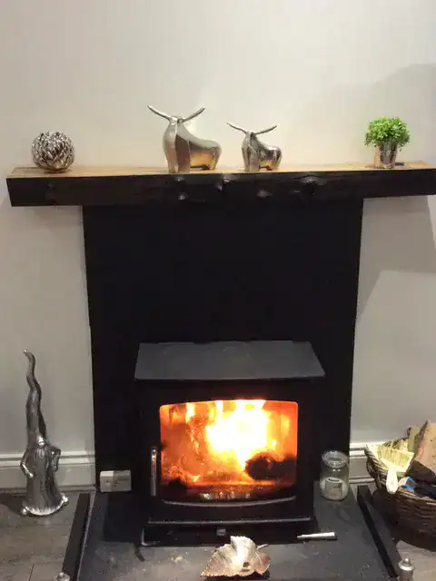 A live edge mantel on top of a woodburning stove, decorations on top - sent by a customer