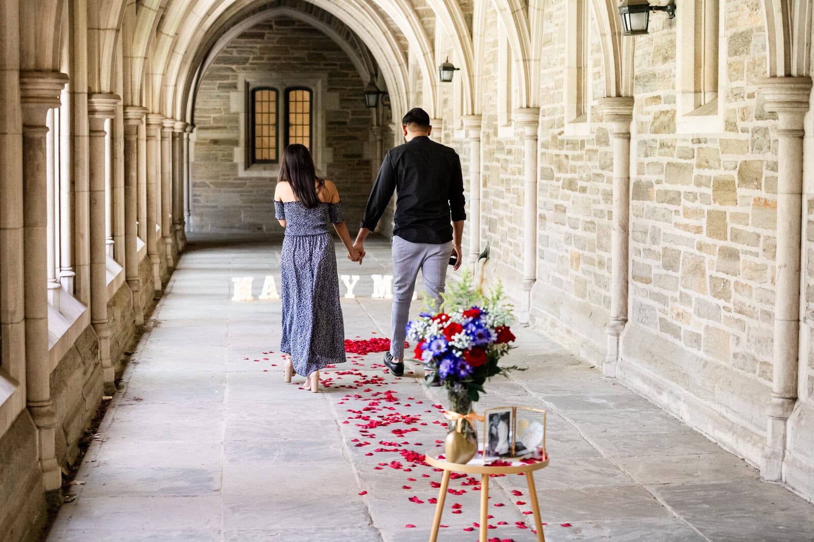 6 Surprise Proposal Tips to Prepare for the Big Engagement! Couple holding hands in arched corridor
