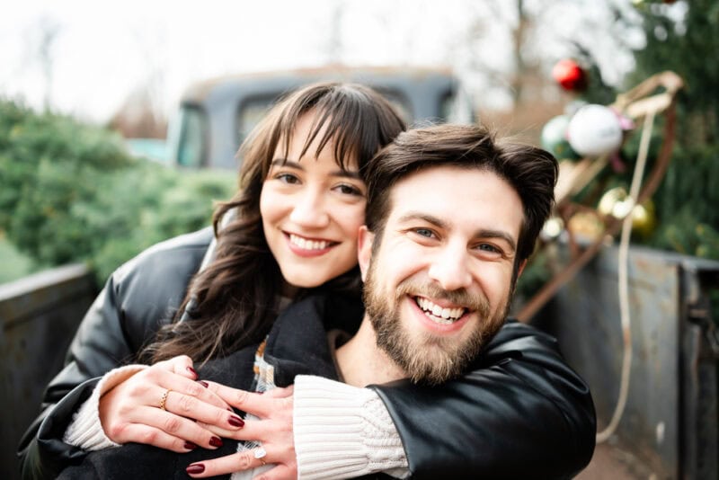 How to Hire a Surprise Proposal Photographer in New Jersey Happy couple hugging with Christmas decorations.