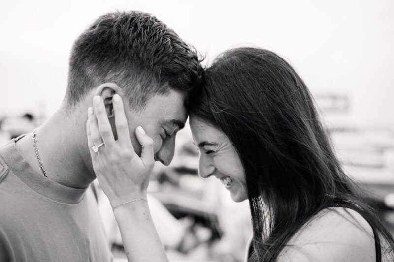 The Psychology Behind Monochrome Photo Processing Couple smiling, touching foreheads, engagement ring visible.