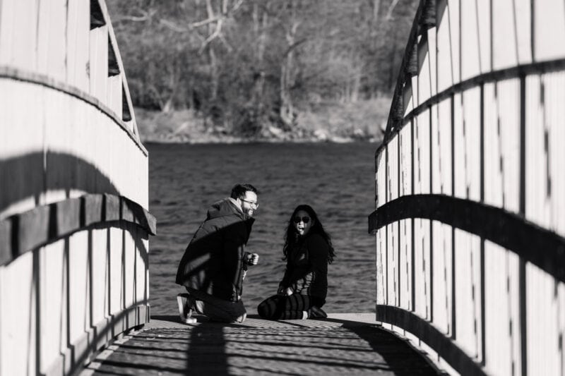 The Perfect Black & White Photo Editing Style Couple kneels on bridge over windy river.
