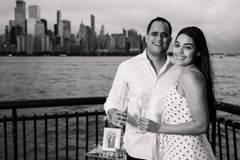 The Perfect Black & White Photo Editing Style Couple celebrating with champagne by city waterfront.