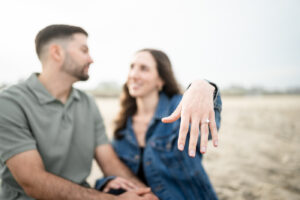 Couple showing engagement ring on beach.