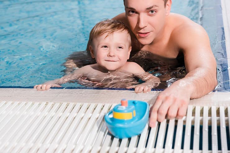 father and son enjoying pool while toy on drainage