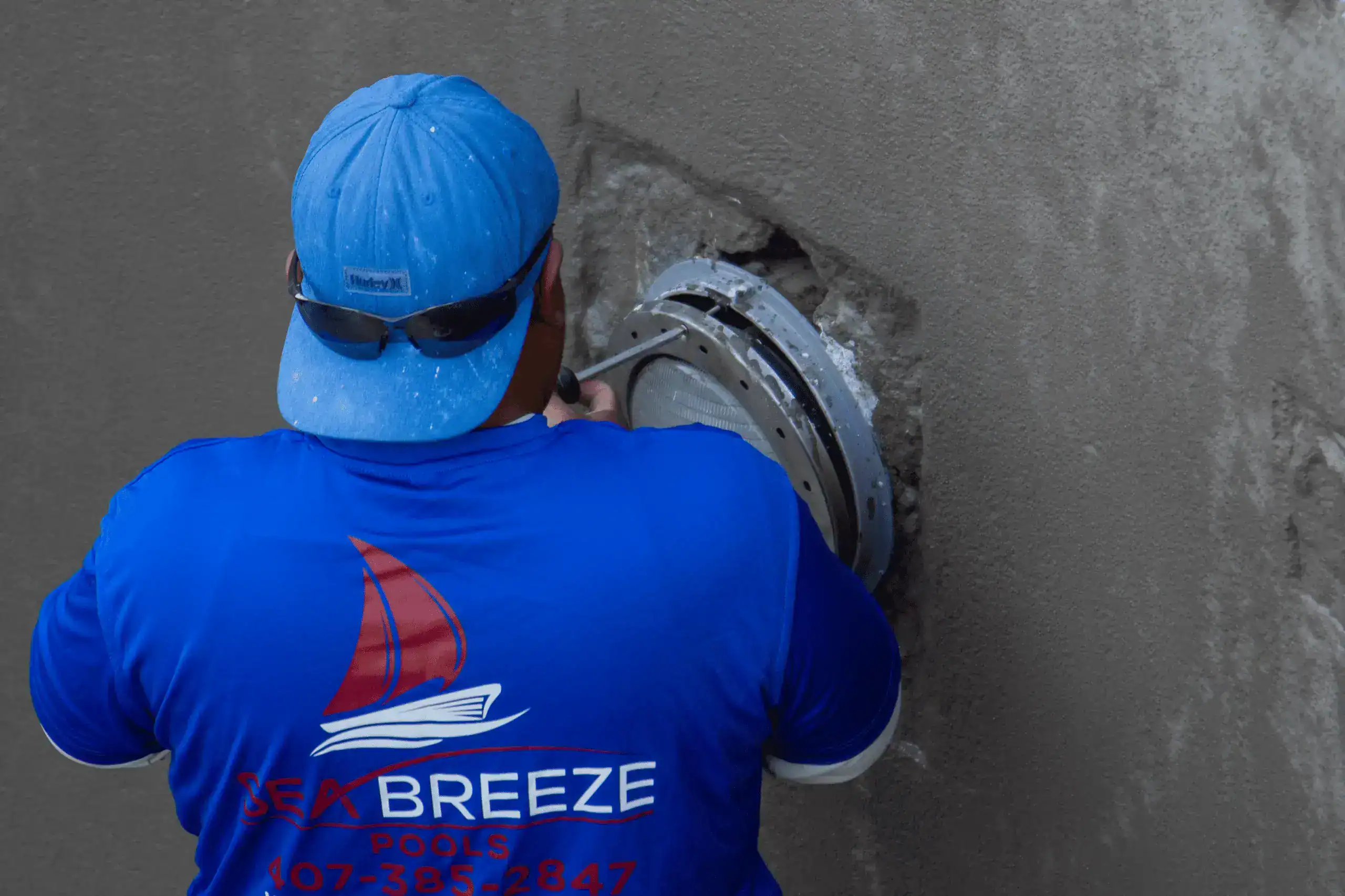 Sea Breeze Pools employee working on fixing a broken light in an Orlando pool.