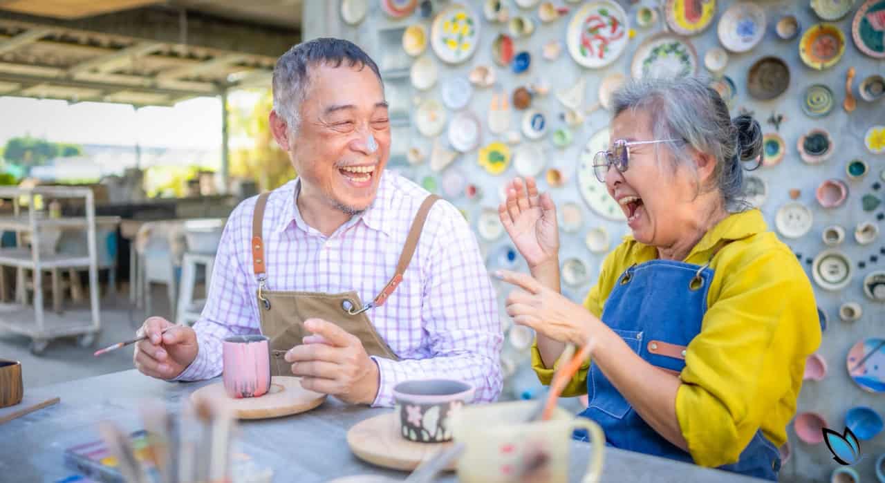 An Asian, Senior Couple having a fun time painting at a senior living community