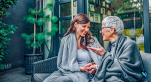 Adult daughter discussing assisted living with her elderly mother on their couch at home