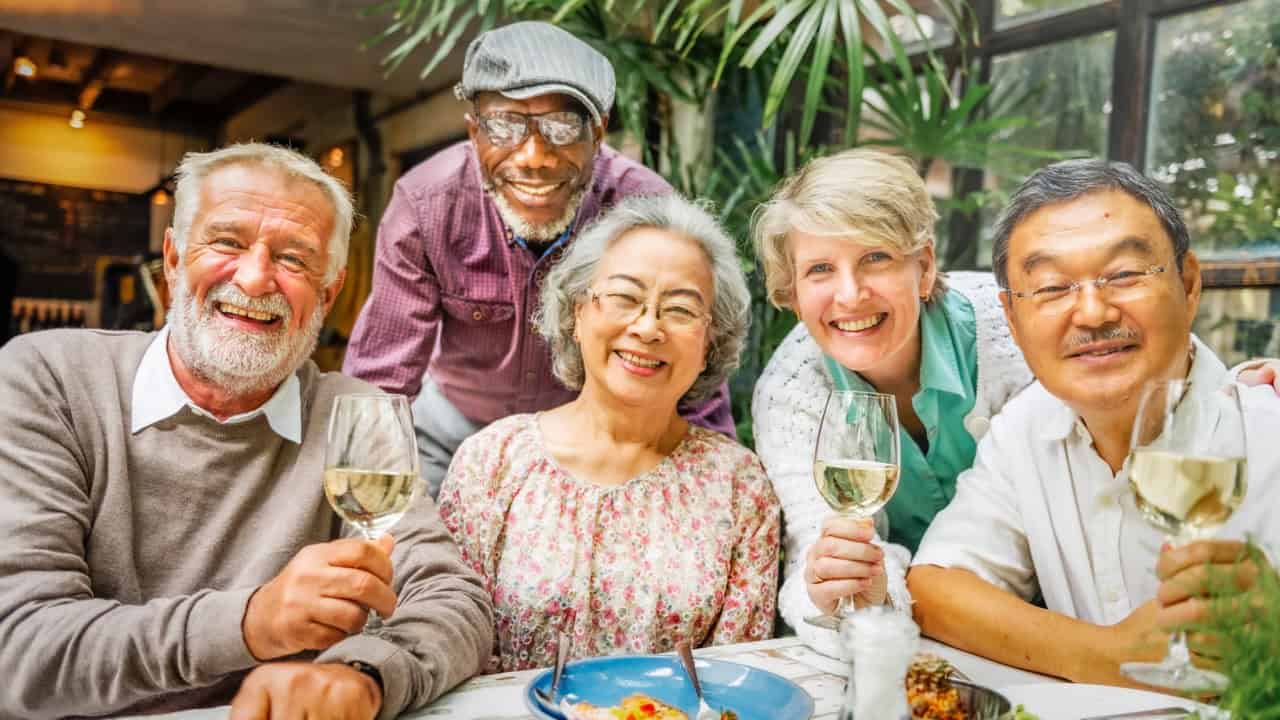 Diverse group of seniors at an assisted living community having fun and drinking wine