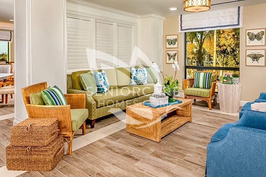 Clearwater Newport Beach living room lounge with green sofa, wicker chairs, and butterfly wall art