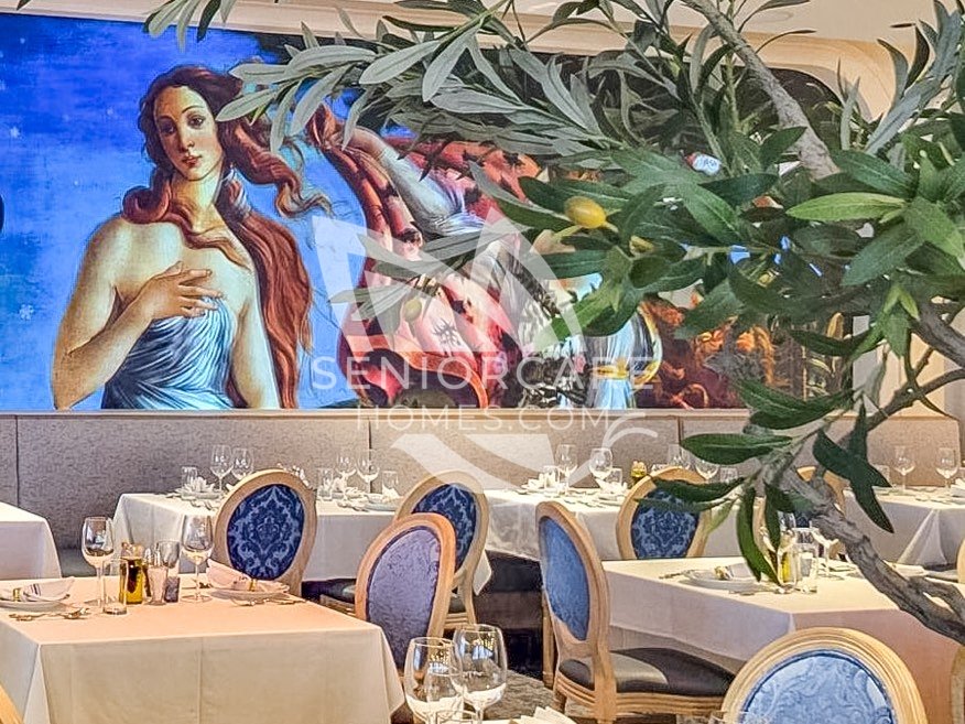 Fine dining room at Clearwater at Pinnacle Peak with white tablecloths, blue upholstered chairs, an olive tree, and a large Renaissance-style mural.