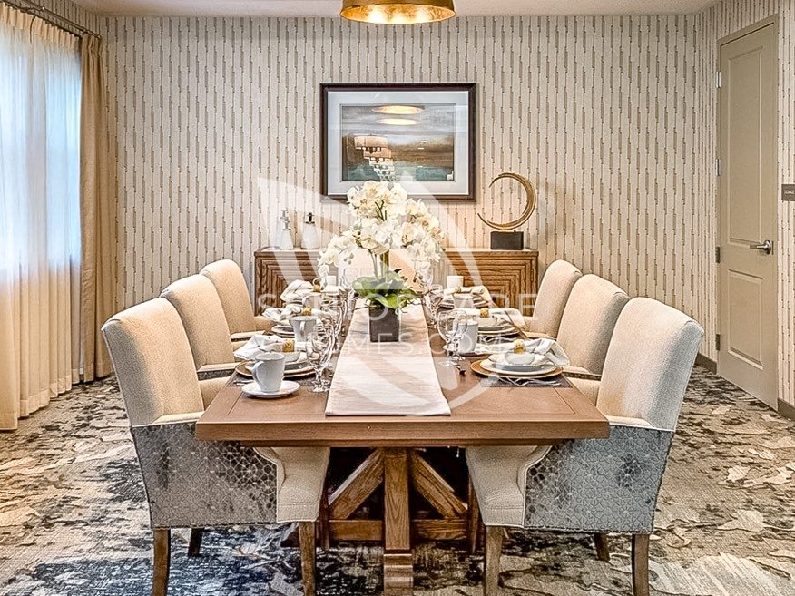 Private dining room at Clearwater at Rancharrah with a farmhouse table set for eight, upholstered chairs, and a white orchid centerpiece.
