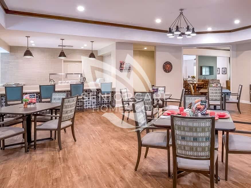 Dining room at Clearwater at Sonoma Hills with patterned upholstered chairs, blue bar stools, pendant lights, and a wall clock.