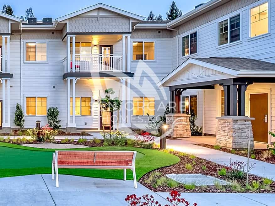 Two-story residential building at Clearwater at Sonoma Hills at dusk, with balconies, a putting green, a bench, and landscaped walkways.