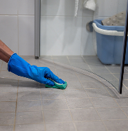 Professional cleaning worker disinfecting restroom floor with spray and cloth.