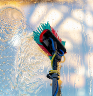 Window cleaning tool with squeegee and scrubber in action on glass.
