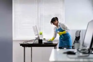 Professional cleaner disinfecting office desk to boost employee productivity and maintain a healthy.