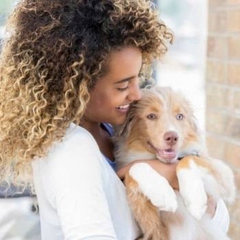 woman holding a young puppy and smiling | Find A Rescue Pet