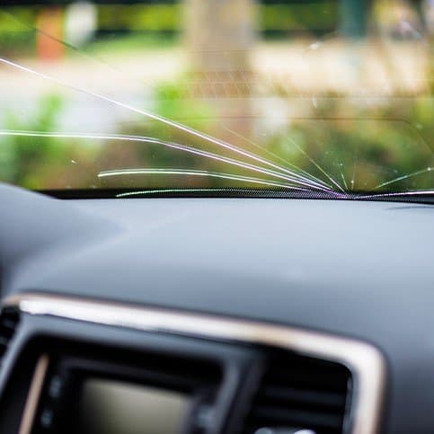 Windshield with stone chip prevention film on car dashboard.