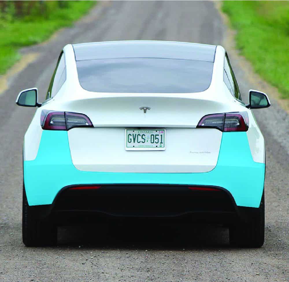 Tesla Model Y electric vehicle on a scenic rural road, showcasing eco-friendly transportation.