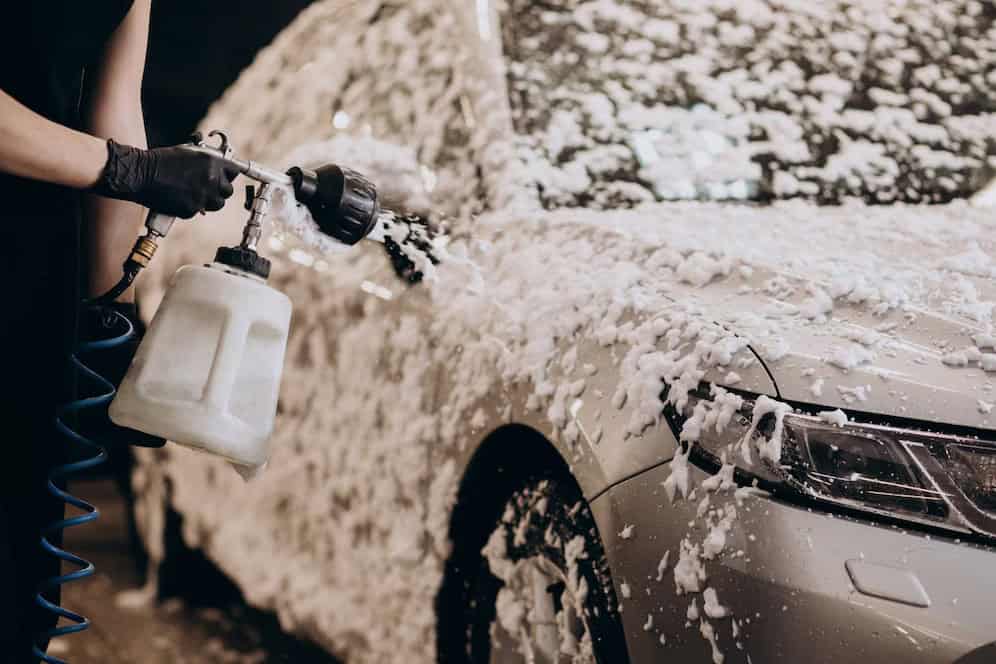 Car being washed with foam and water during pre-PPF detailing process.