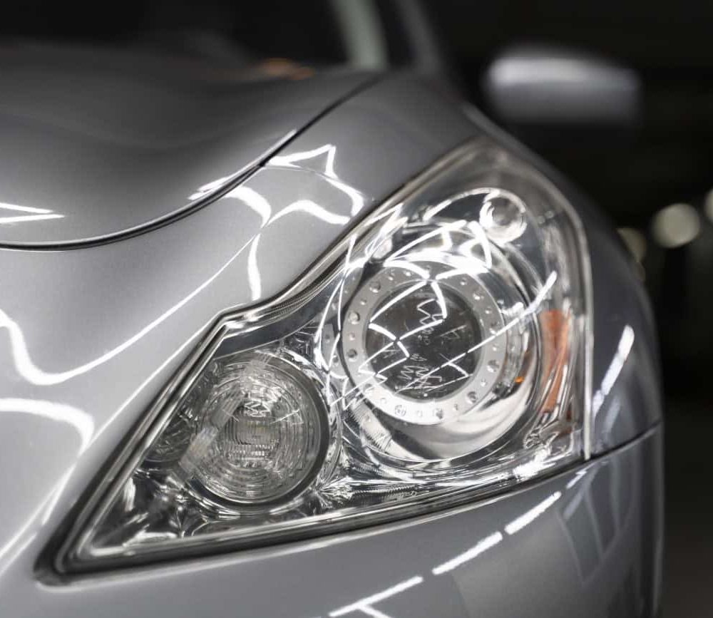 Close-up of car headlight with PPF protection during XPEL detailing.