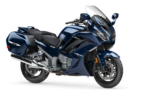 Blue touring motorcycle with side panniers and windshield for long-distance rides.