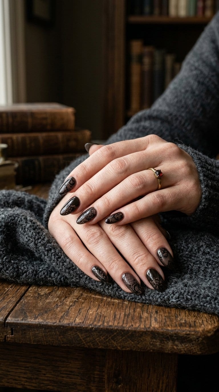 Hands with black lace-patterned nails resting on a dark sweater.