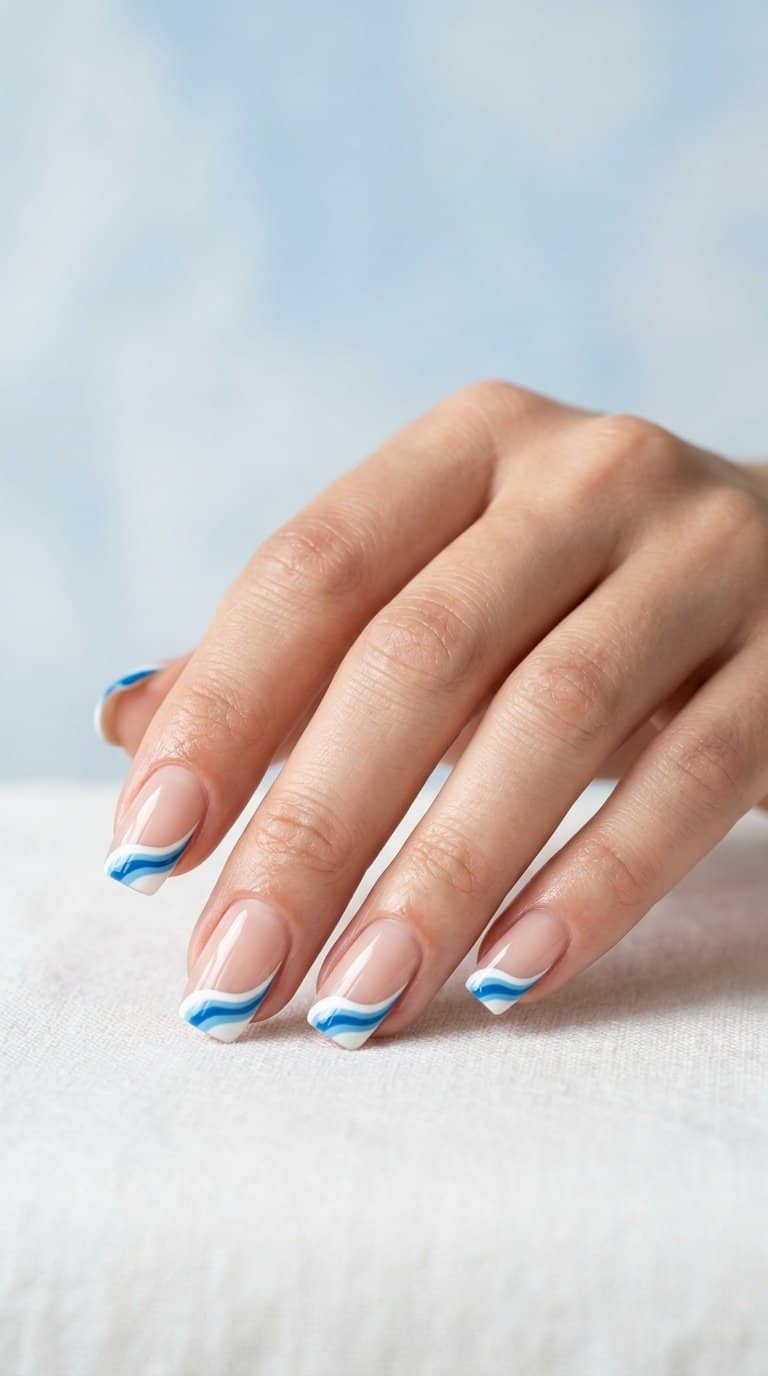 A hand with blue-and-white wave French tip nails.