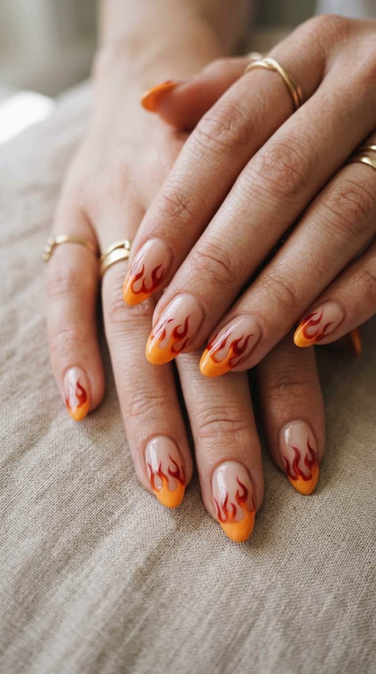 Close-up of manicured hands with glossy orange and red flame-shaped French tips.