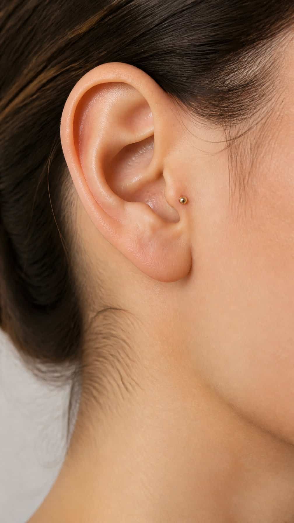 Close-up of an ear with a small bead piercing on the anti-tragus.