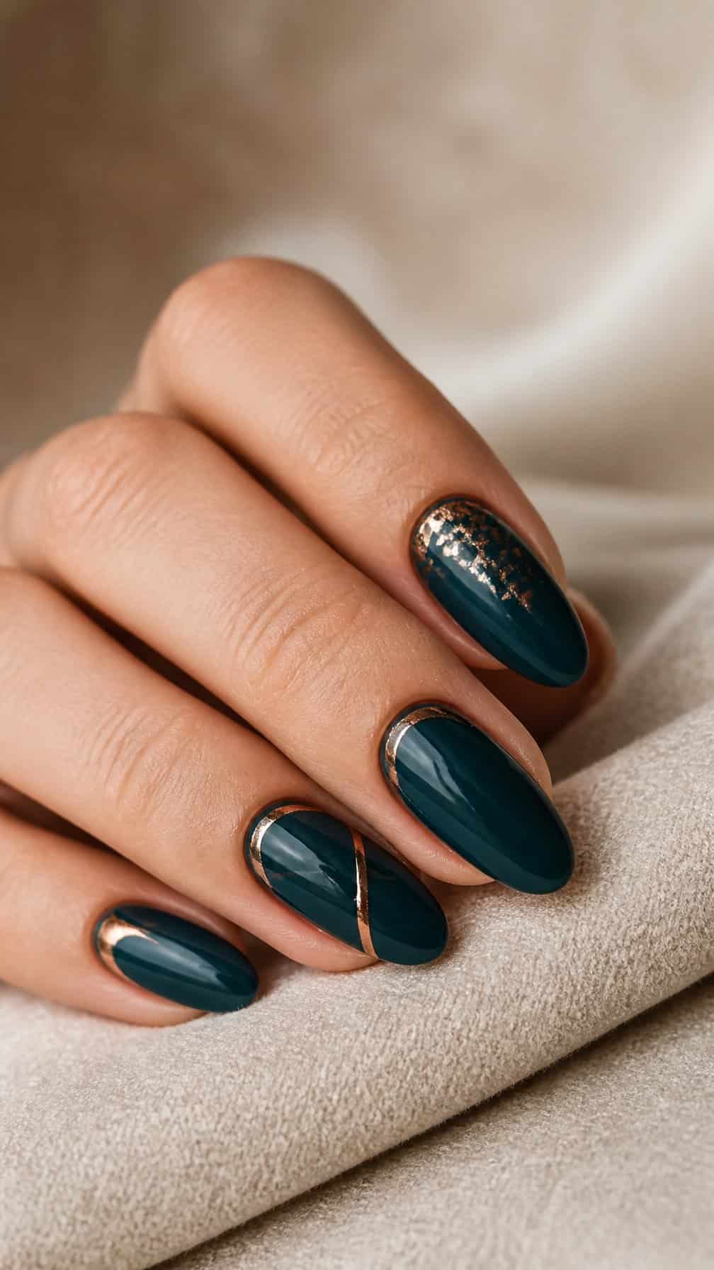 A hand displays dark teal manicured nails with delicate copper accents.