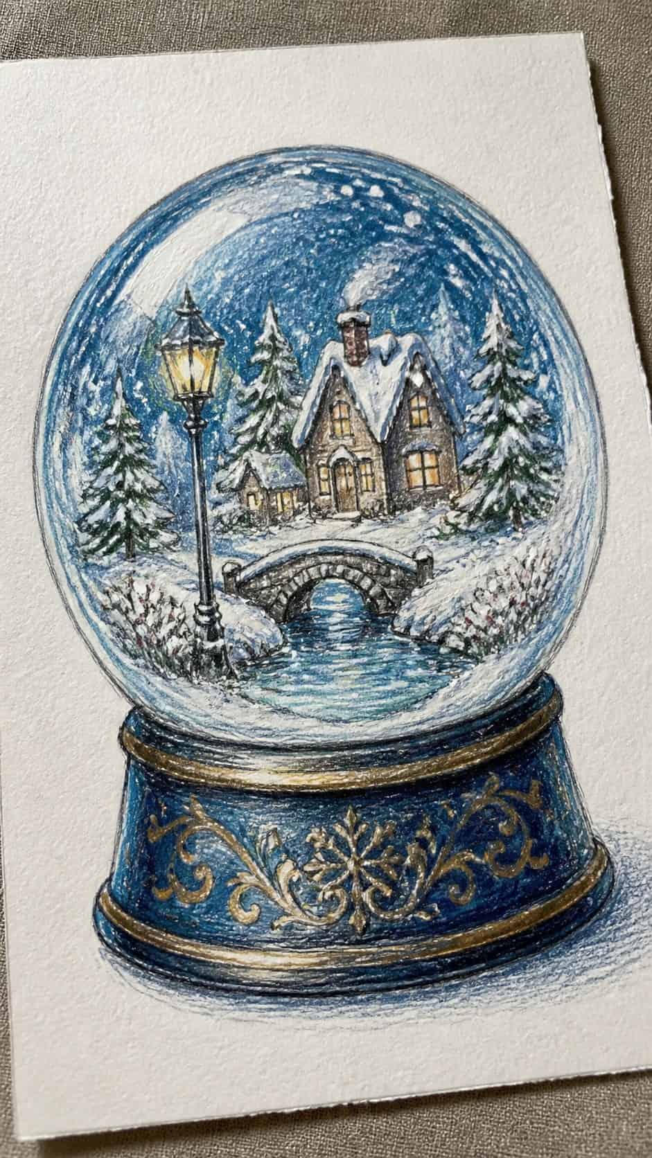 15 Christmas Drawing Ideas to Try This Holiday Season 3 Hand-drawn enchanted snow globe scene in colored-pencil and gouache drawing on textured paper, shown in a gentle oblique desk view — study 2