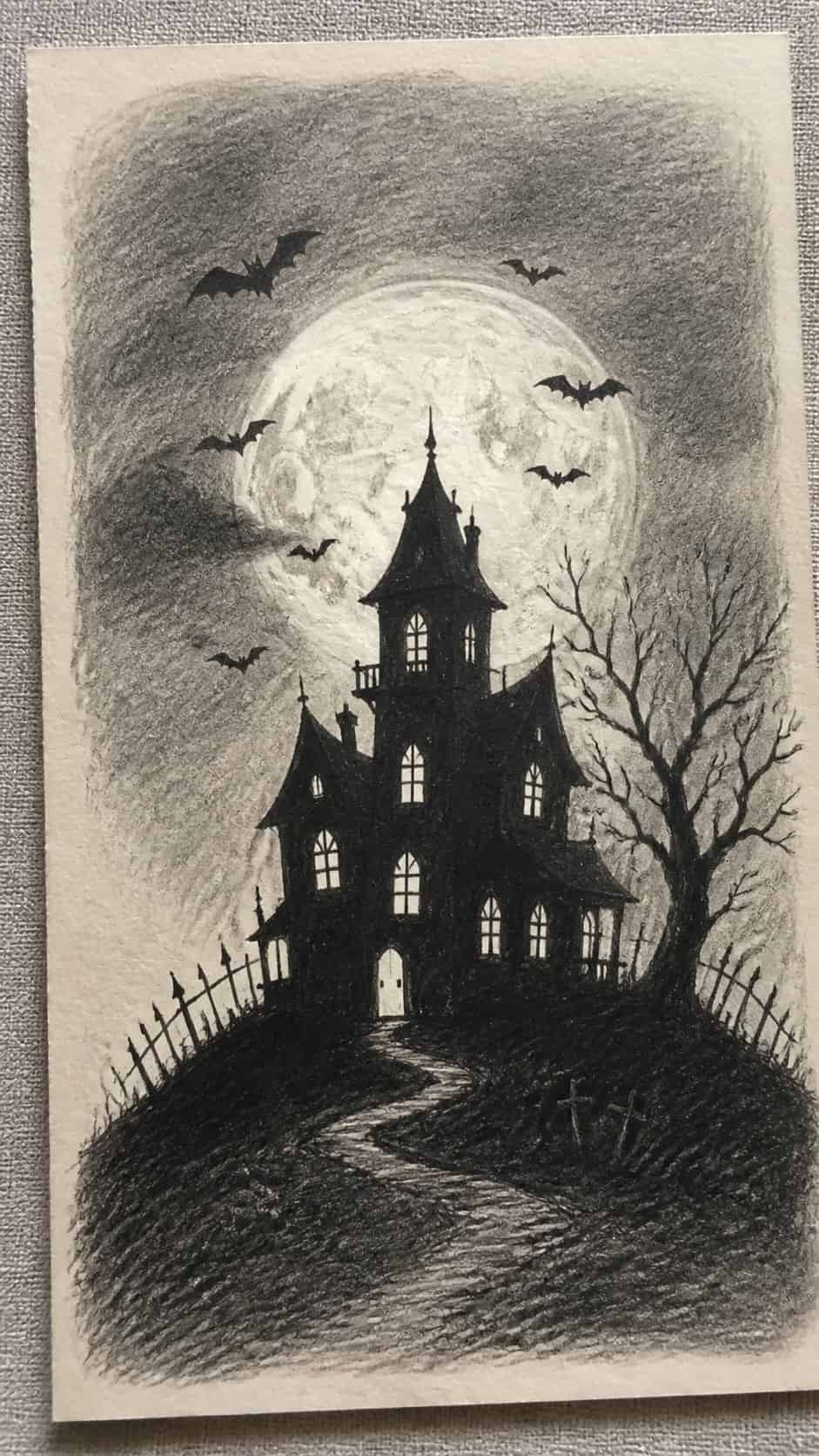 18 Ghost Drawing Ideas for Spooky and Expressive Sketches 6 Hand-drawn haunted house silhouette in graphite drawing on textured paper, shown in a close overhead crop — study 1