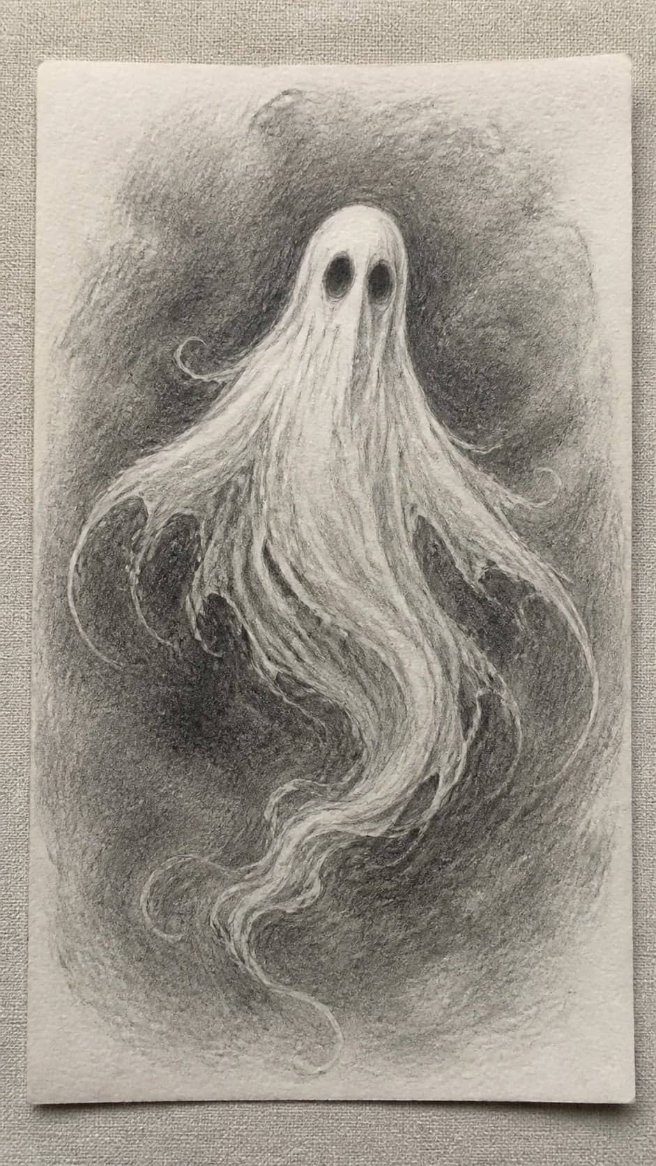 18 Ghost Drawing Ideas for Spooky and Expressive Sketches 9 Hand-drawn mysterious floating ghost in graphite drawing on textured paper, shown in a straight overhead view — study 1