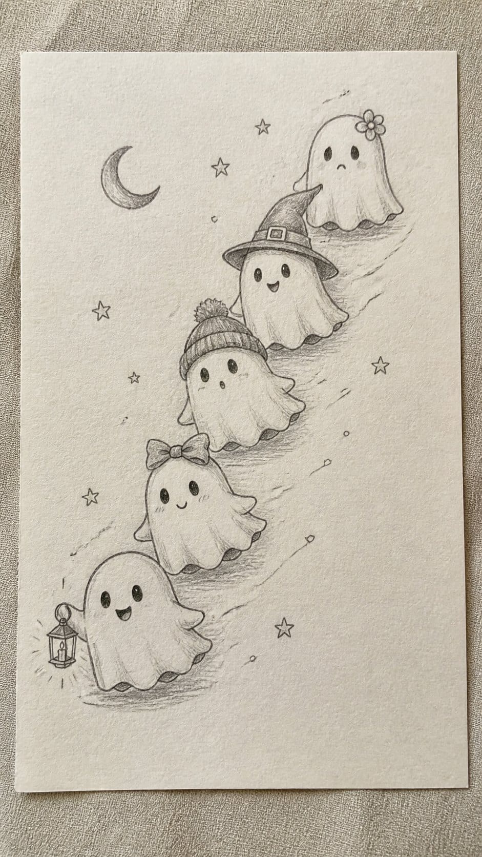 18 Ghost Drawing Ideas for Spooky and Expressive Sketches 13 Hand-drawn mini ghost parade in graphite drawing on textured paper, shown in a close overhead crop — study 1