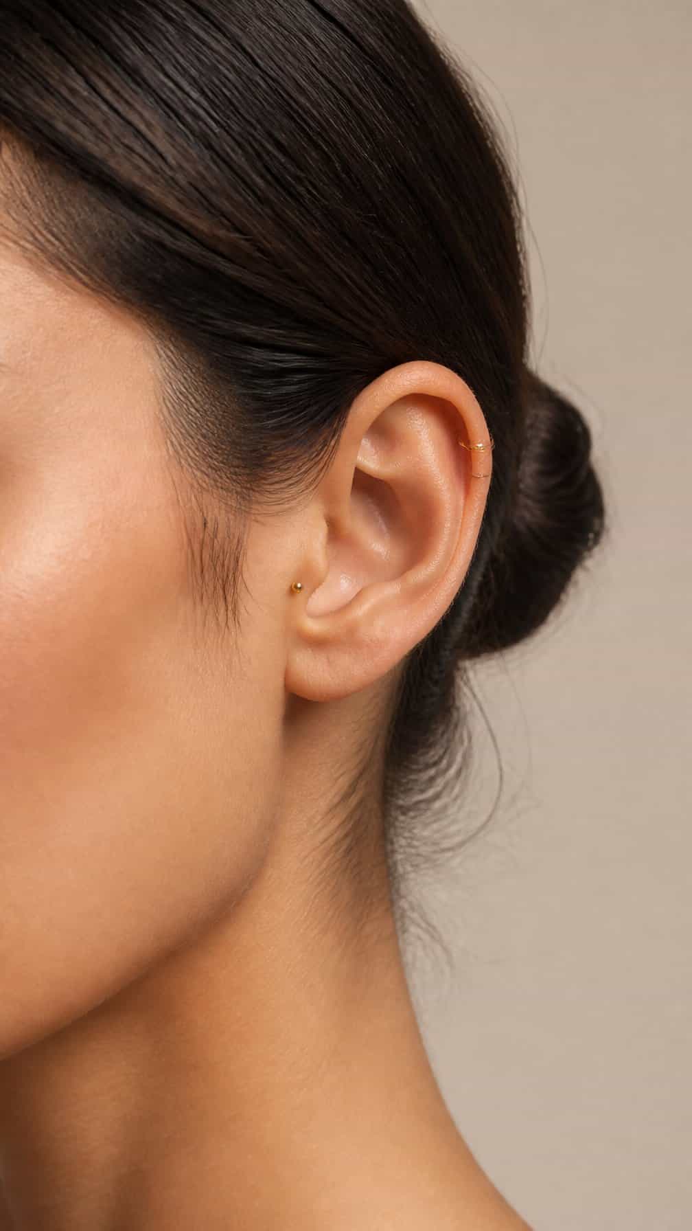 Close-up of an ear featuring coordinated forward helix and tragus piercings.