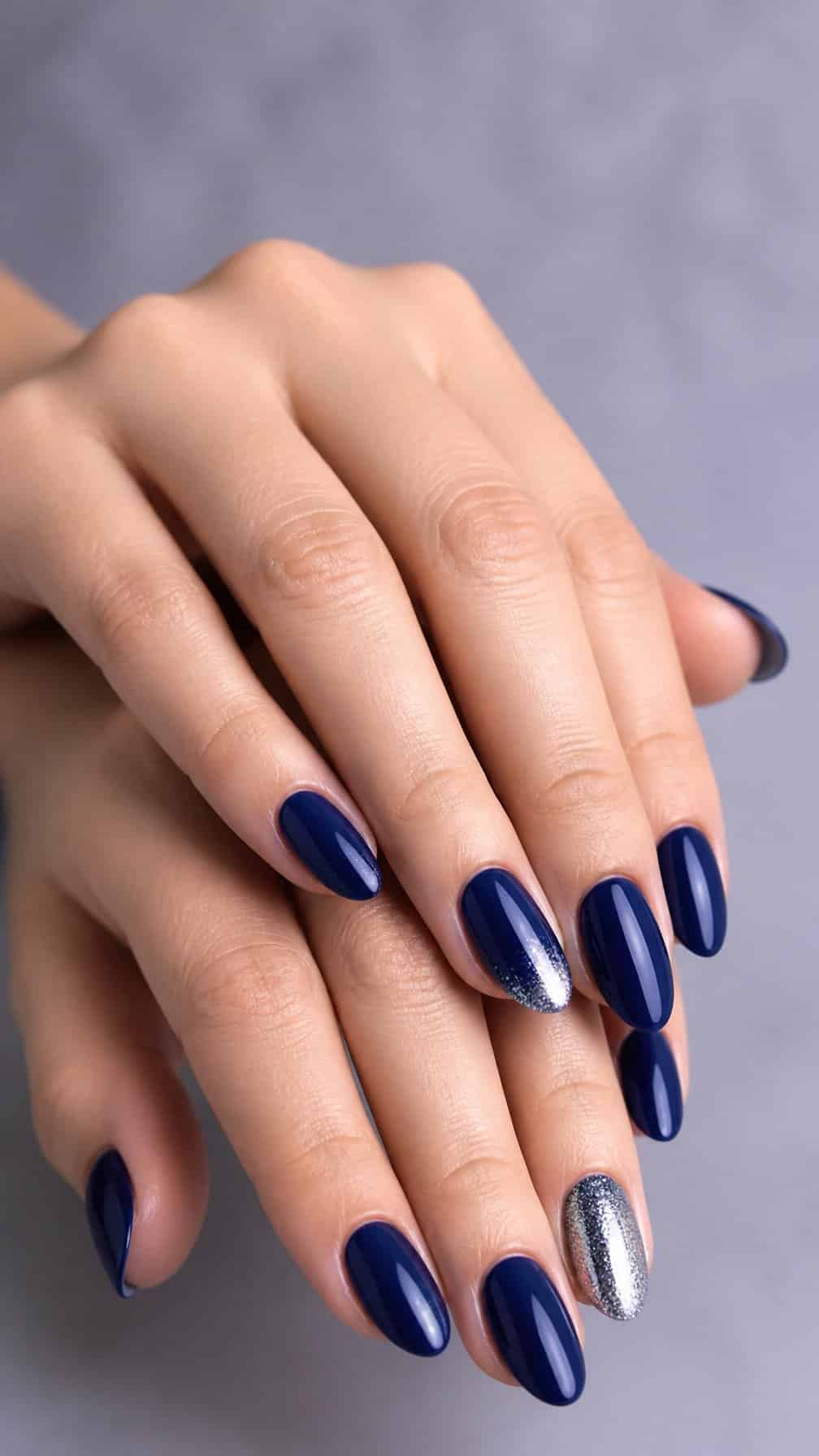 A close-up of hands with deep indigo nails and silver glitter accents.