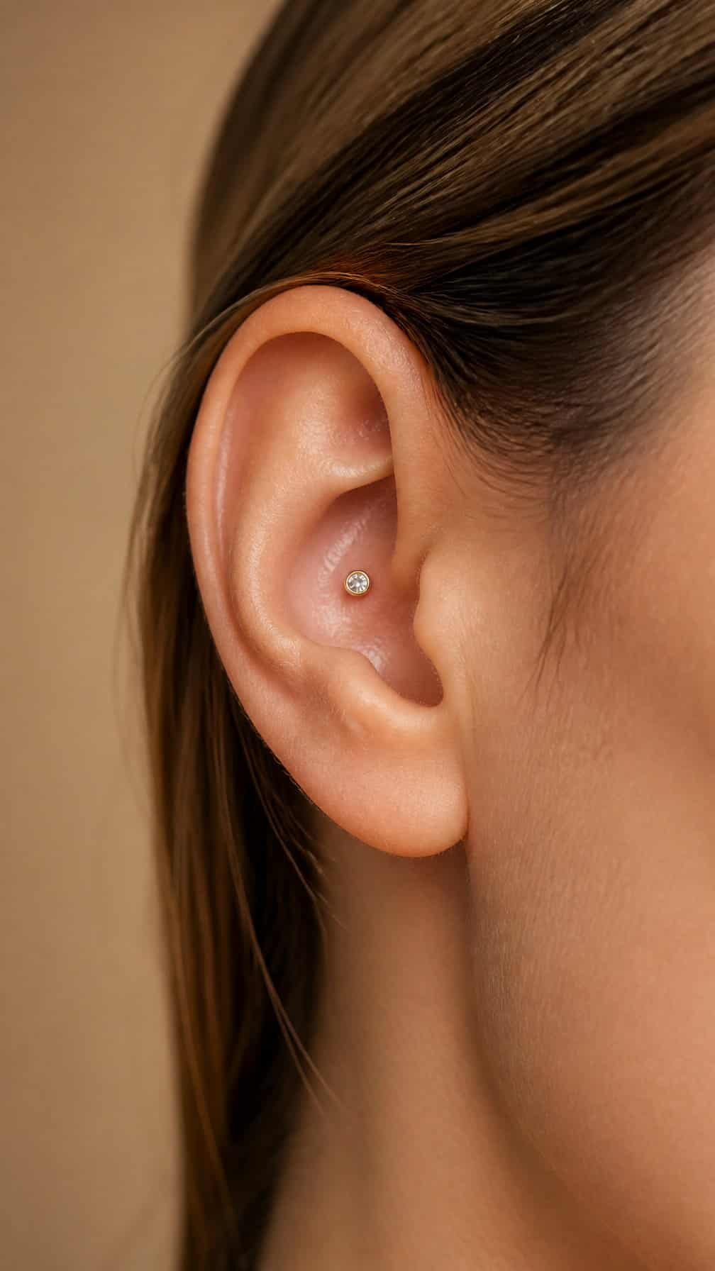 Close-up of an ear with a small bezel-set stud in the inner conch.