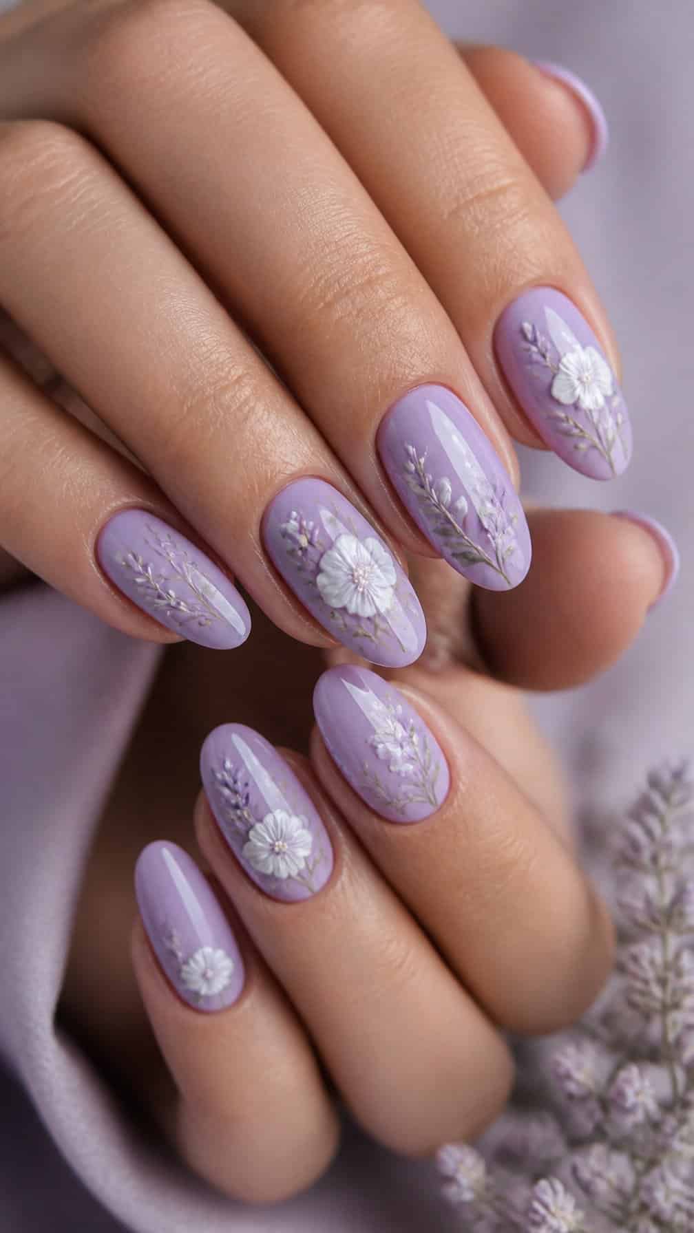 A close-up of a hand with lilac nails decorated with white flowers.
