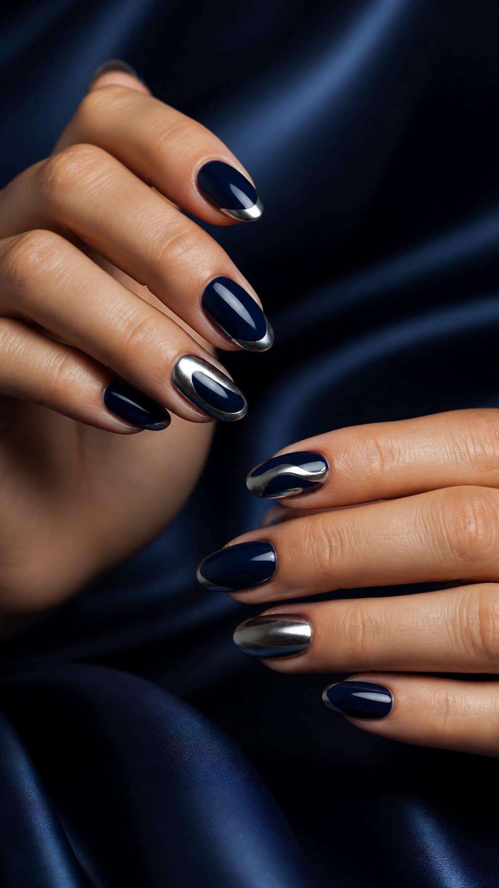A close-up of manicured hands with glossy midnight navy nails and silver chrome accents.