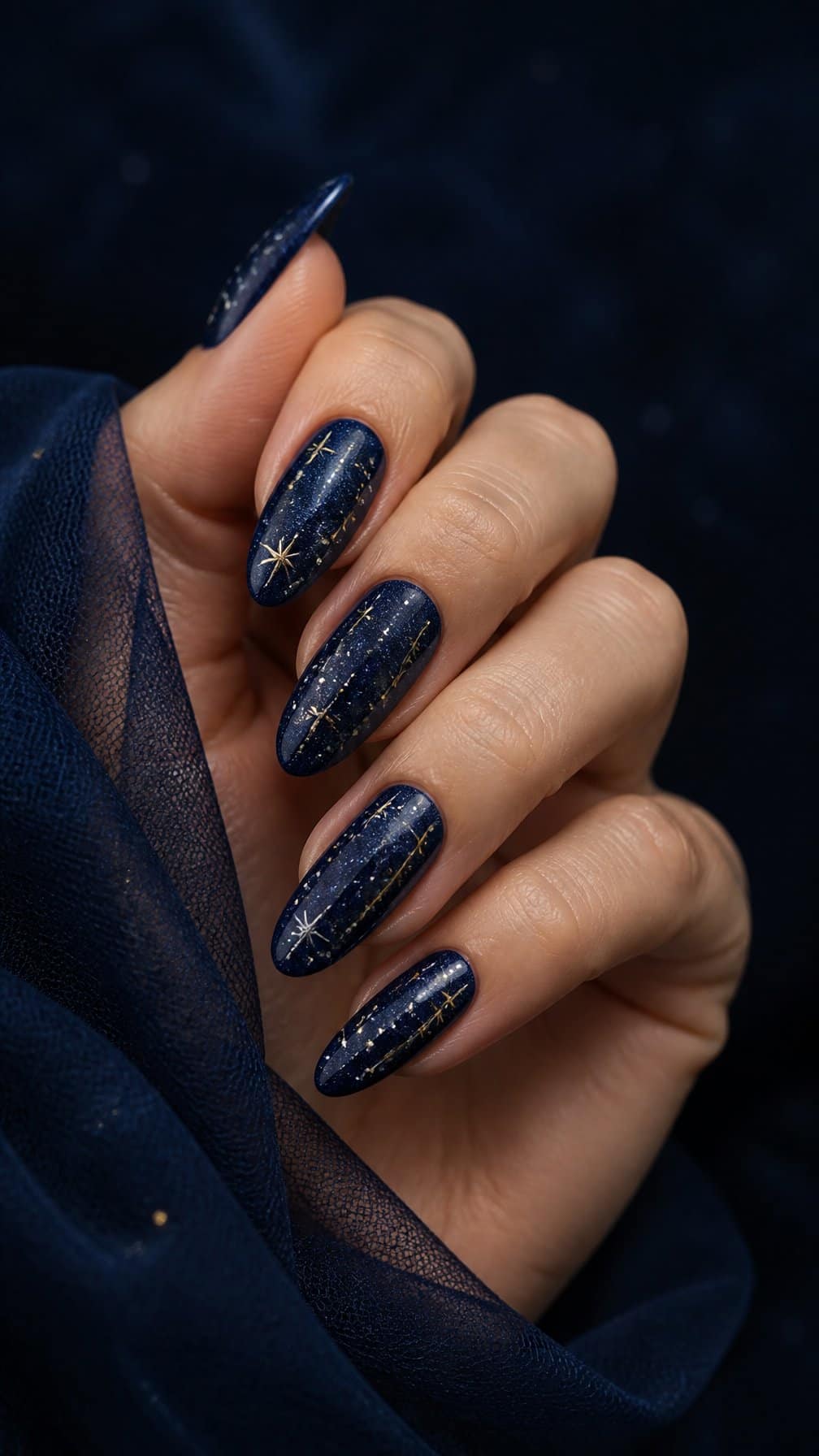 A hand displays a navy blue manicure decorated with small celestial stars.
