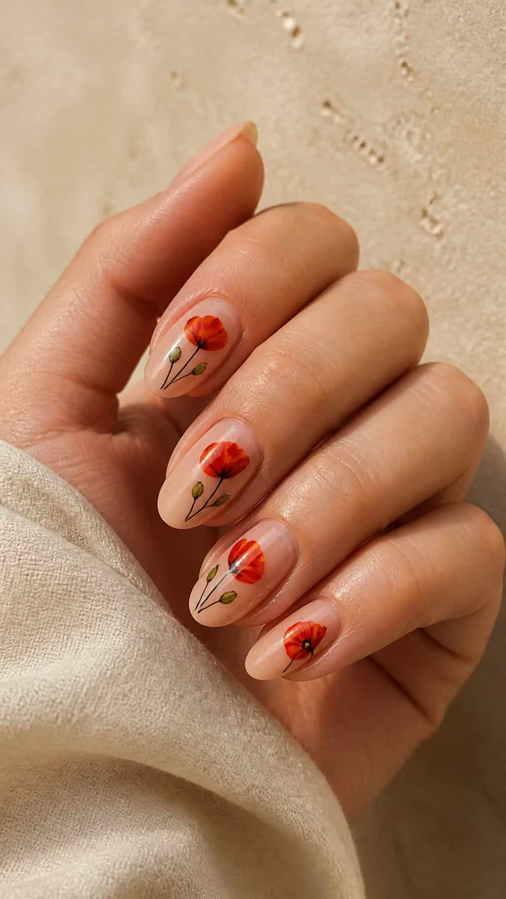 A hand with elegant red poppy designs painted on natural-toned nails.