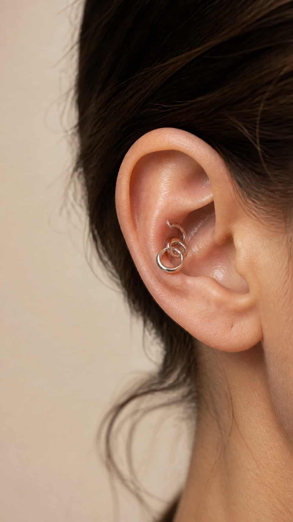 Close-up of an ear with interconnected rings arranged through the conch area.