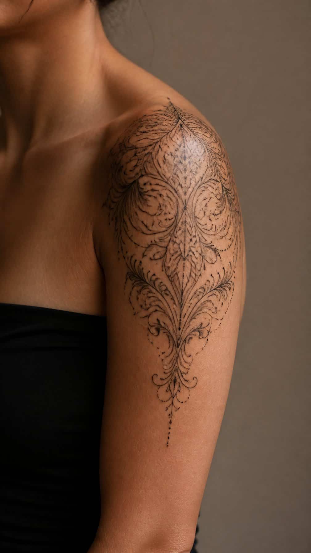 Close-up of an ornamental filigree tattoo flowing from a person's shoulder onto the upper arm.