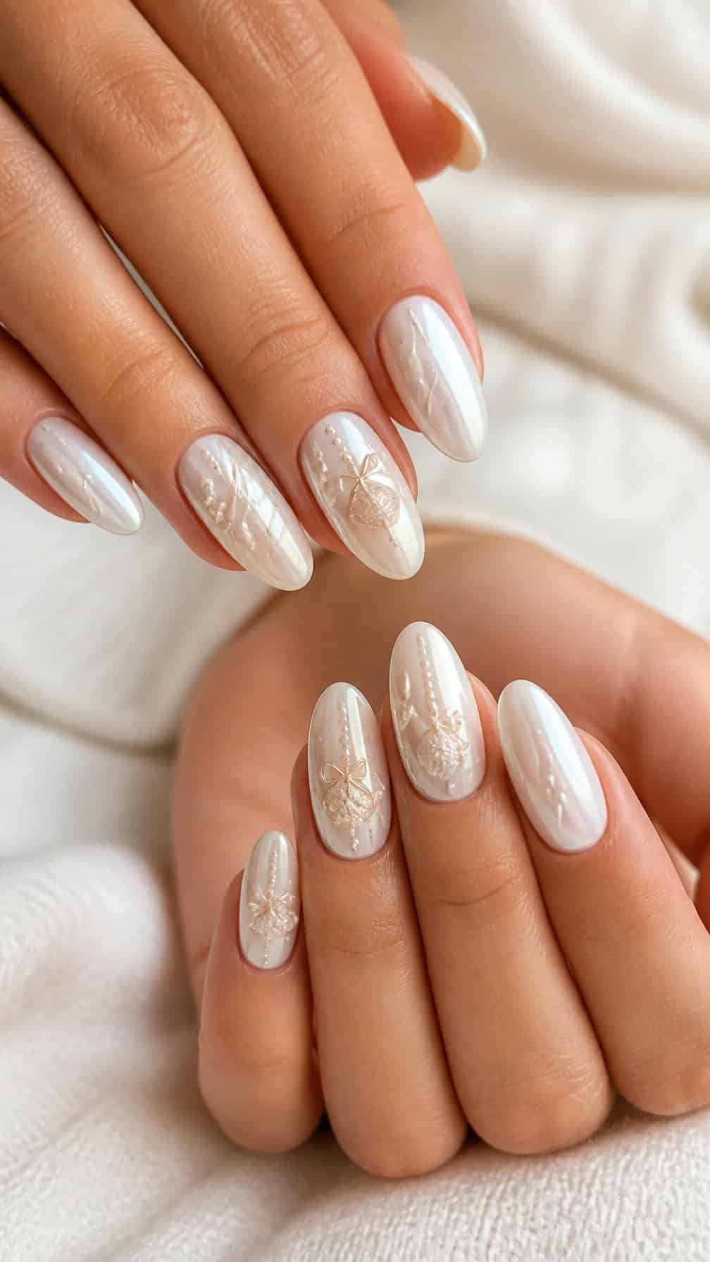 Close-up of hands with glossy pearl white ornament-inspired nail designs.